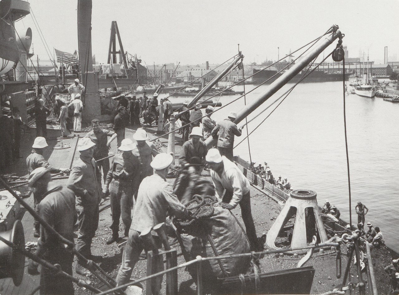 A photograph of sailors packing large bags which used to transfer the coal.