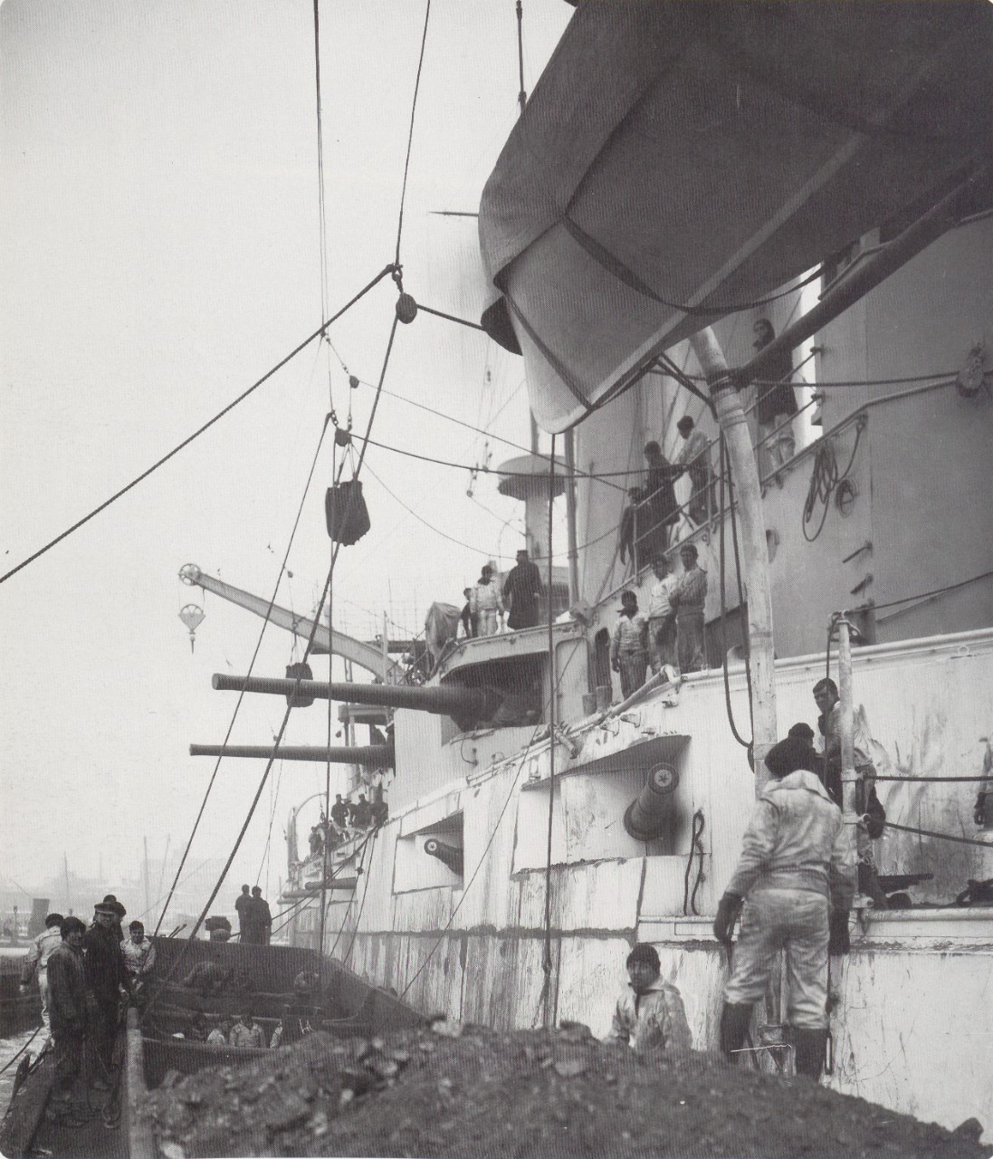 A picture of hoisting coal onto a ship with cranes.