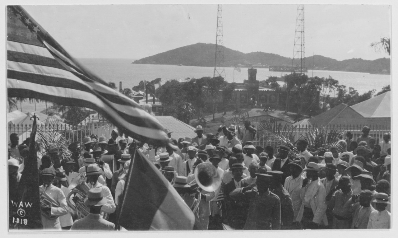 Photograph of a large crowd gathered under an American flag