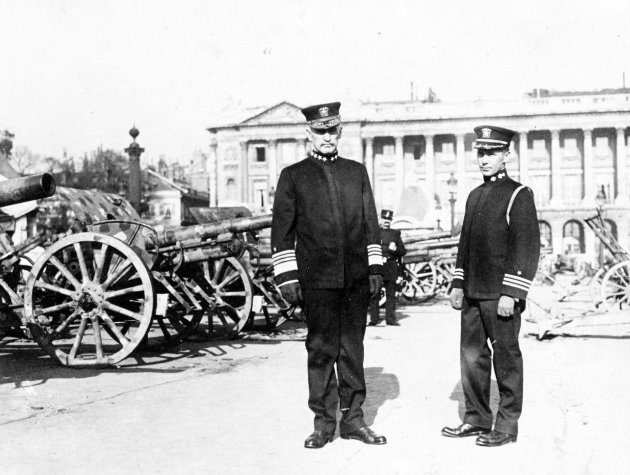 Benson standing beside a row of cannon in front of a Parisian hotel