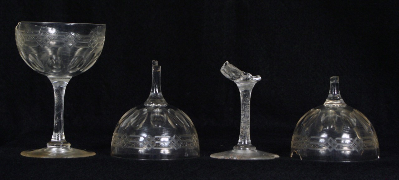 One complete and three fragmented clear glass stemware recovered from CSS Alabama. The bowl’s design has three parallel lines near the rim that cross at intervals to create a diamond shape and ten cut oval depressions encircling the bottom.  The bowl tapers to the stem of the glass and enlarges at the base. 