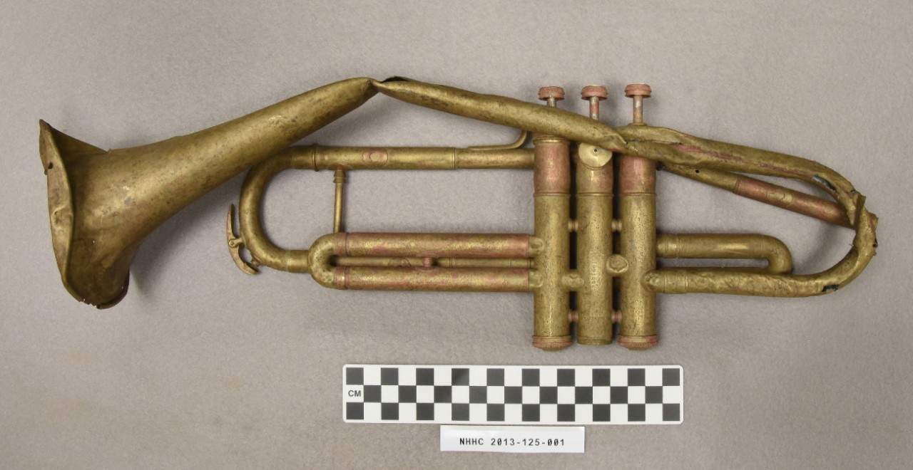 <p>Brass trumpet with mother of pearl valve buttons from the USS Houston wreck site. &nbsp;It is damaged with various cracks, bends, and dents, The trumpet is mainly gold in color with a few places where a copper color shows through.</p>
