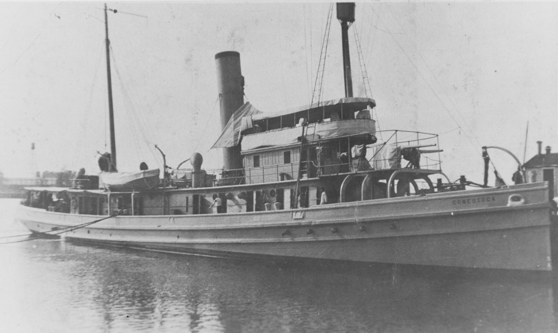 Black and white photograph of a steel tug boat with sails down.